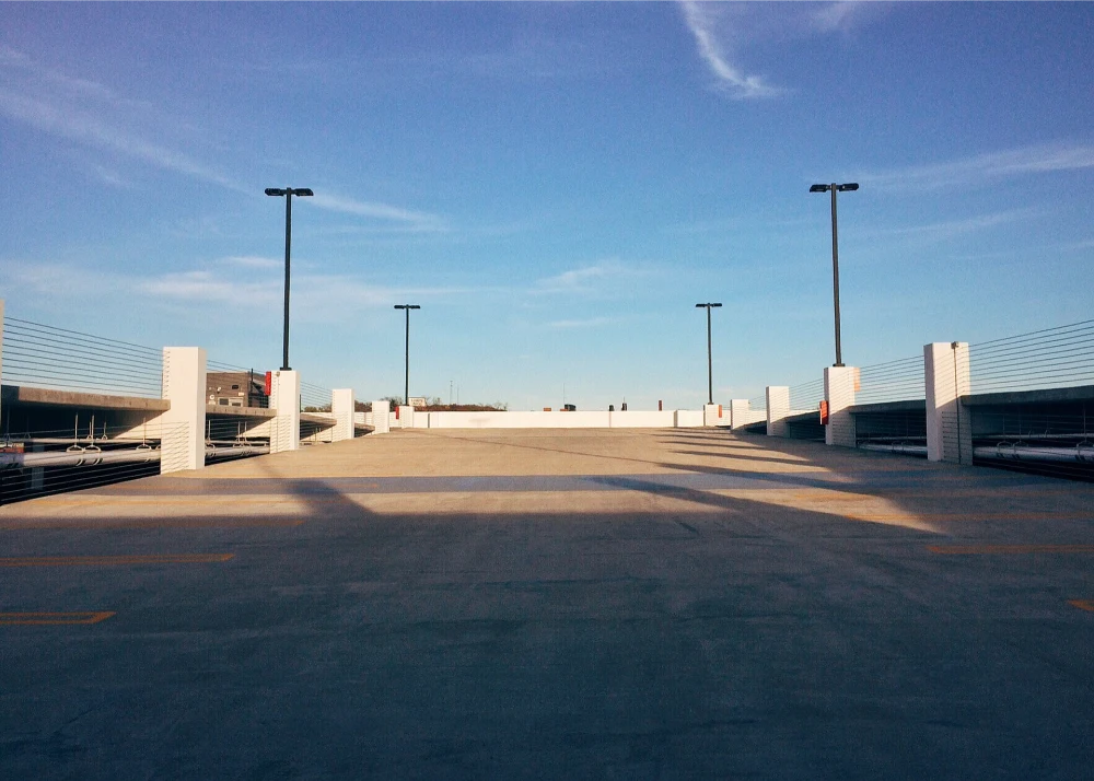 Large empty parking lot with lighting and safety barriers, illustrating potential slip and fall accident hazards.
