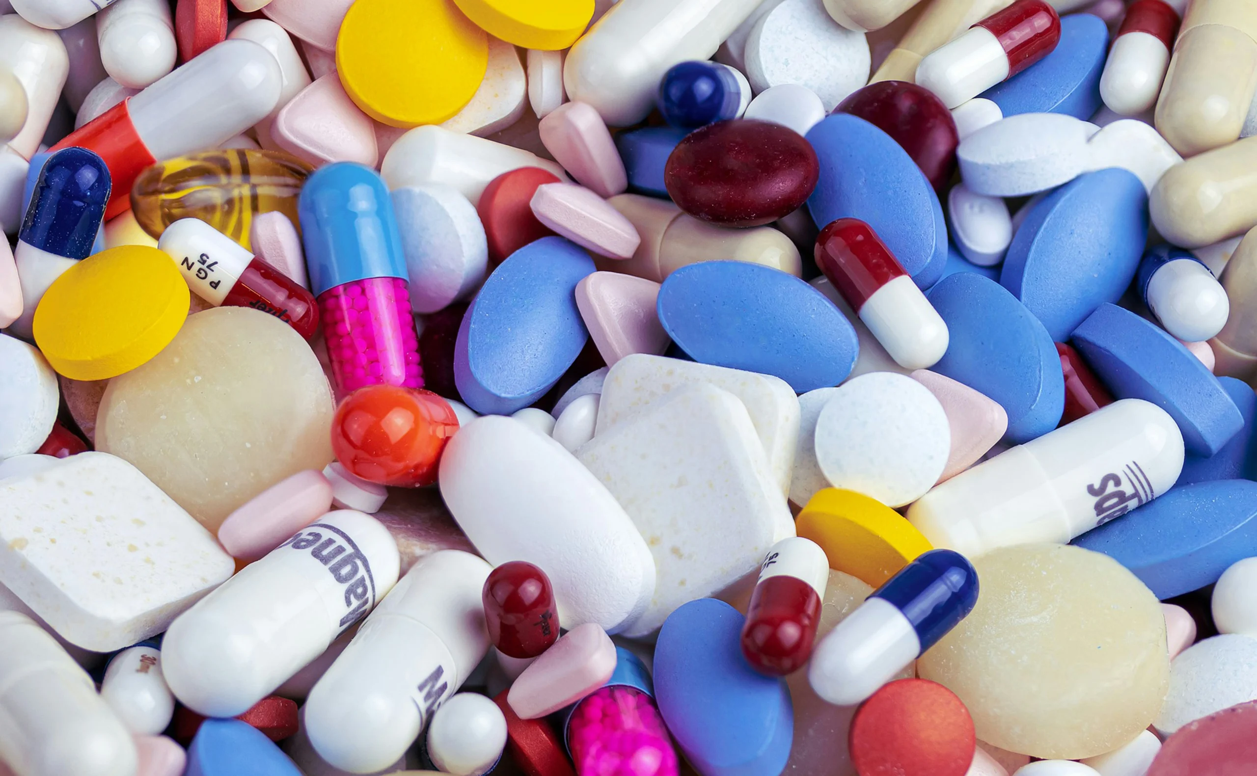 Assorted pills and capsules representing defective drugs and adverse side effects.